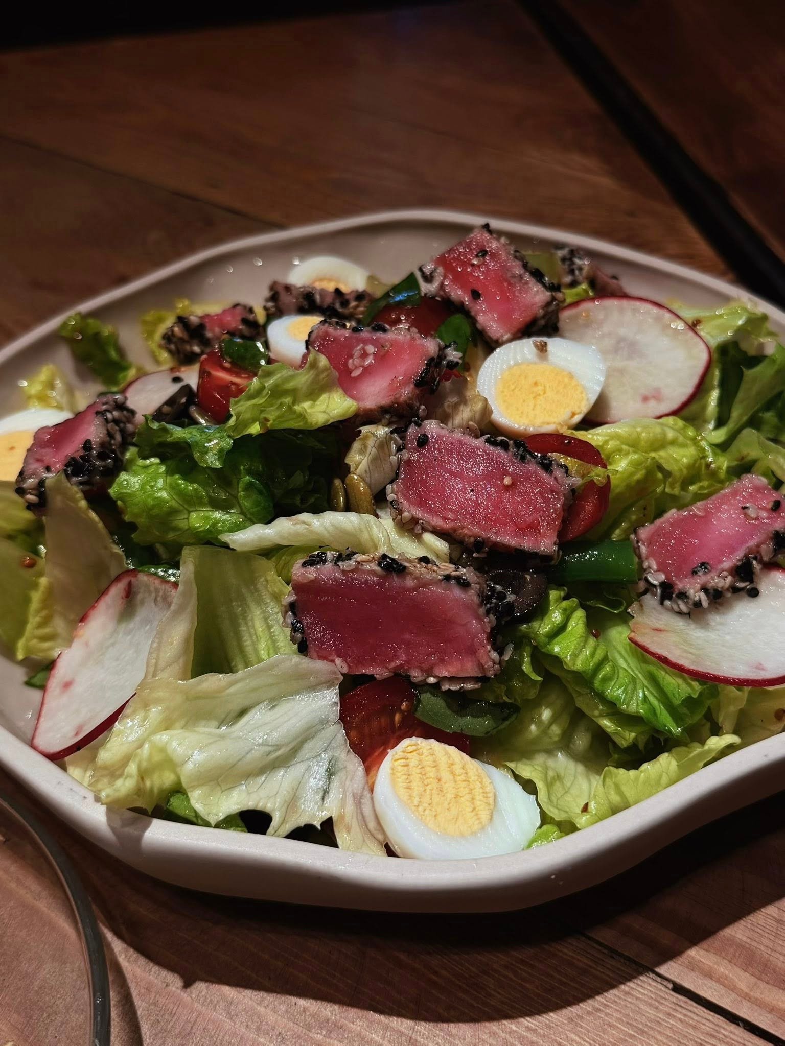 A composed salad course with seared tuna, greens, radish, and egg.
