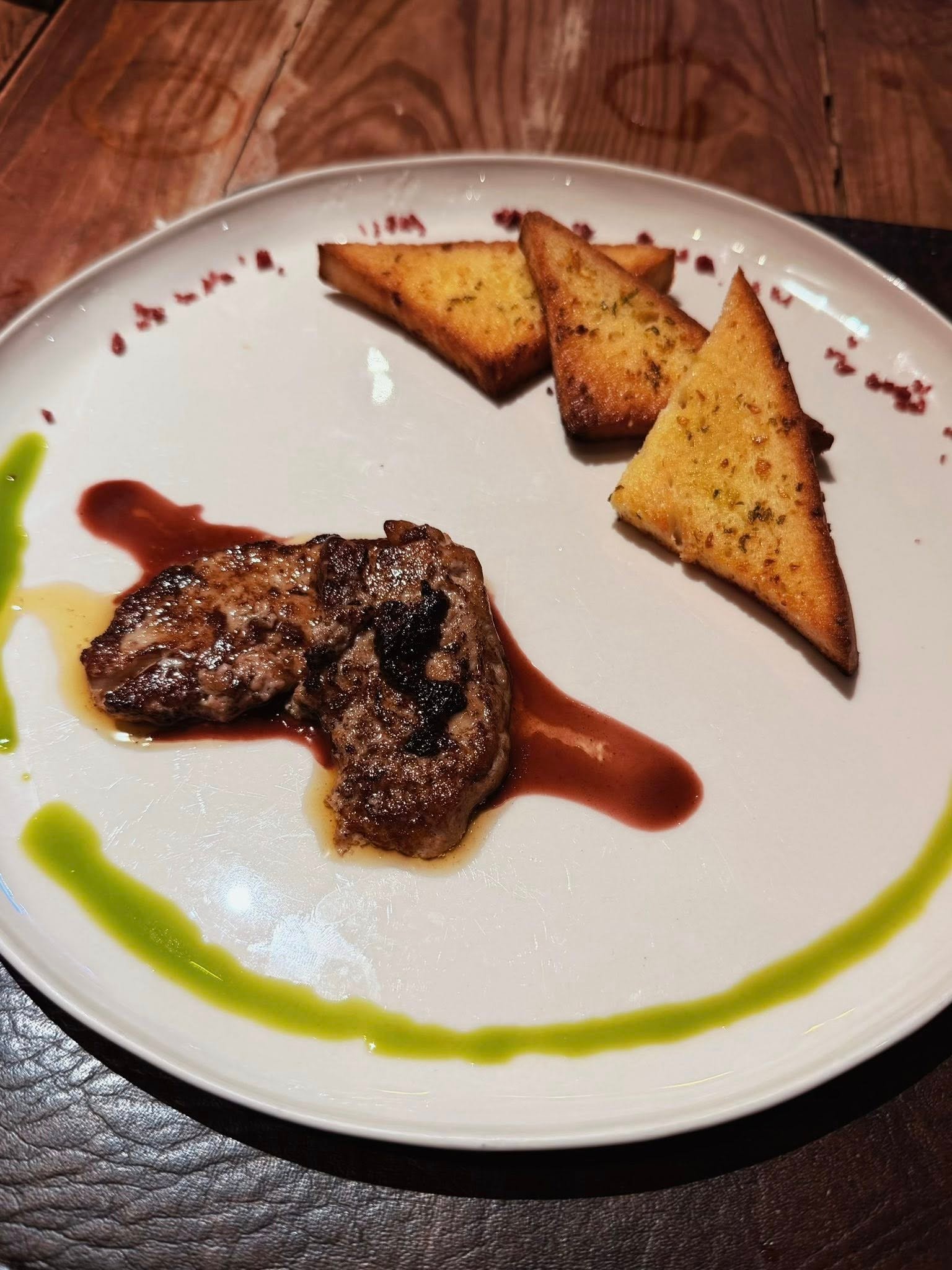 A plated main course with grilled meat, toast, and vibrant sauces.